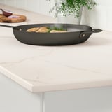 Cuisine moderne avec plan de travail en porcelaine MÖCKLARP et poêle à frire noire.
