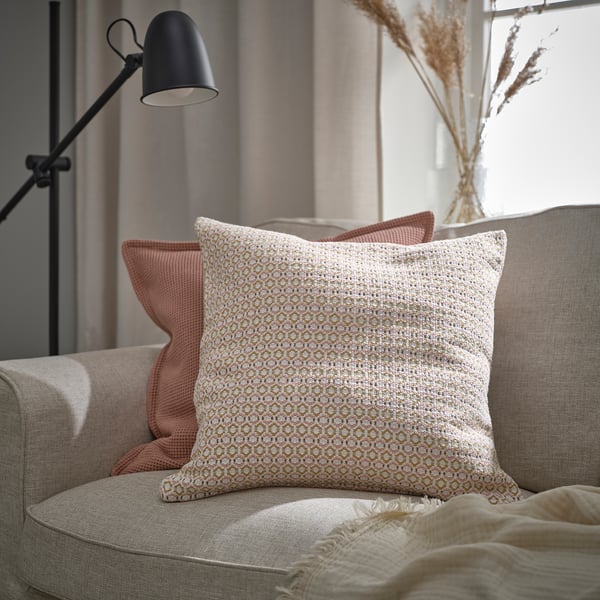 Fauteuil confortable avec coussin MOROTSMOTT, coussins pêche, couverture beige et lampadaire.