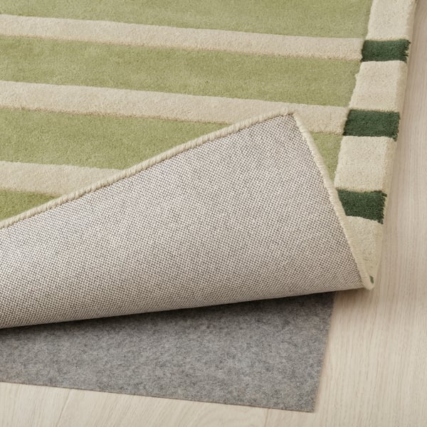 Le coin du tapis rayé montre le dessous avec un support en feutre pour une meilleure adhérence.
