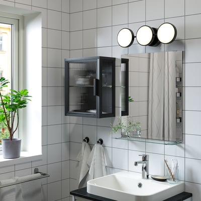 L’armoire murale MOSSJÖN en noir avec une porte en verre dépoli, présente un design élégant et moderne avec une fermeture de porte magnétique.