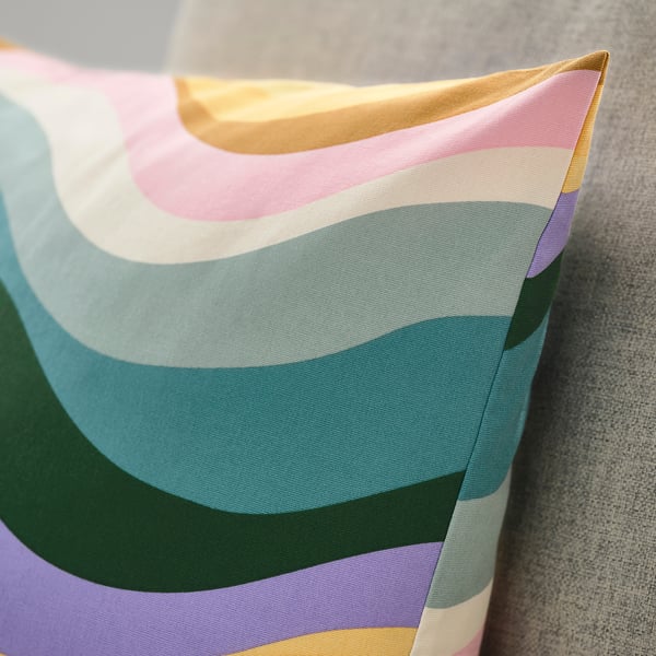 Coussin vibrant et coloré avec des motifs ondulés, du coton de haute qualité, une texture douce et des détails de fermeture éclair.