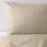 Gros plan d’une housse de couette lisse et luxueuse avec des rayures subtiles, mettant en valeur un tissu de haute qualité.