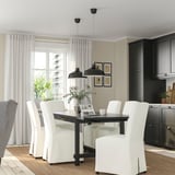 Salle à manger moderne avec chaises NORDVIKEN autour d’une table extensible, suspensions noires, fenêtre, cuisine sombre, chaise à motifs.