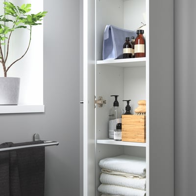 Une armoire de salle de bain haute NYSJÖN blanche avec une seule porte et des pieds en métal.