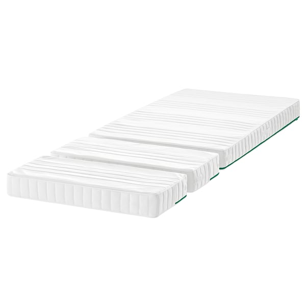 Trois matelas blancs empilés, rectangulaires avec des bords verts, conçus pour grandir avec un enfant.