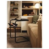 Salon moderne avec canapé beige, coussin vert et table d’appoint OLSERÖD avec cahier et bol.