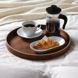 Plateau en bois avec carafe à café, tasse et croissant, parfait pour servir le petit-déjeuner au lit.