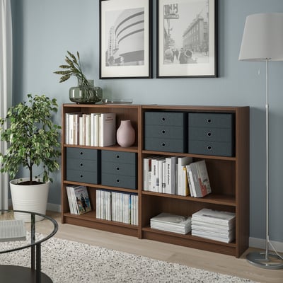 Meuble de rangement en bois PALLRA avec tiroirs gris contre les murs bleus, contenant des livres et de la décoration. Lampe, plante et photos à proximité.