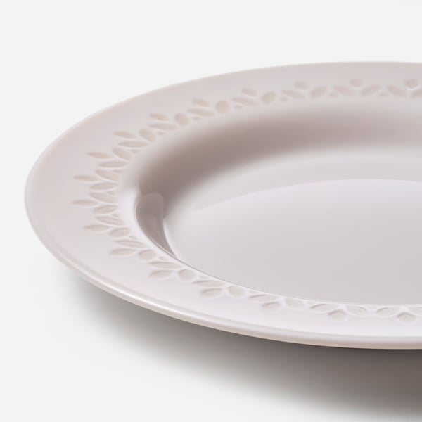Assiette plate blanche avec rebord complexe et texturé ; semble robuste, élégant.
