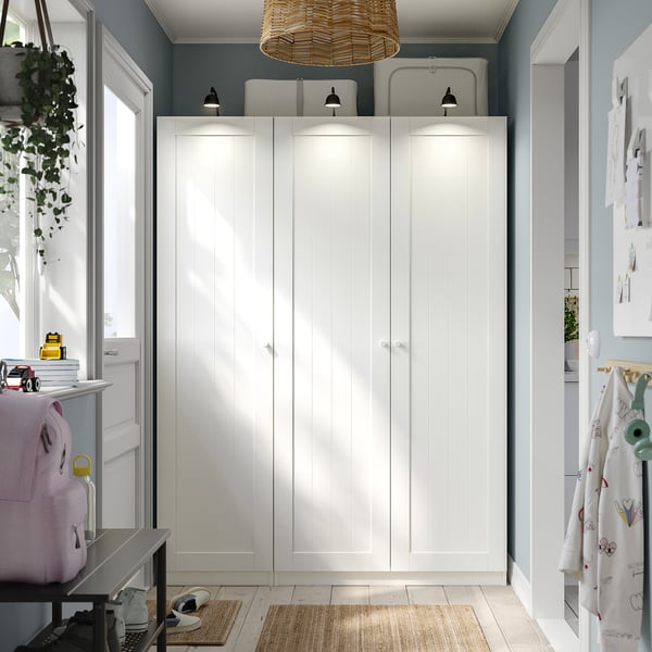 Armoire PAX blanche moderne avec lumières, mur bleu, meubles plus petits.