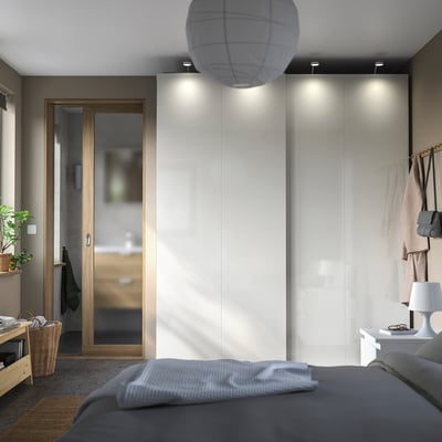 Chambre moderne avec armoires PAX, portes coulissantes, lit gris et éclairage tamisé.