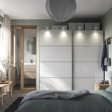 Chambre moderne avec armoires PAX blanches, accents en bois et décor gris.