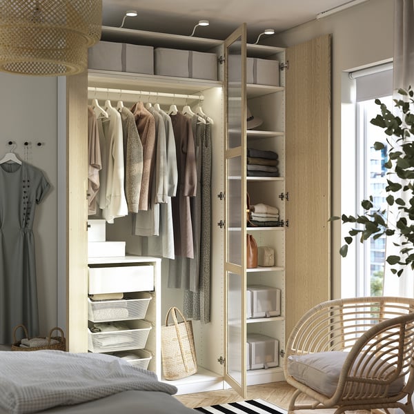 Chambre moderne avec armoire ouverte, vêtements organisés et éclairage intégré.