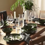 Dressage de table PELARKAKTUS vert foncé avec de la vaisselle, de la verdure et des bougies.