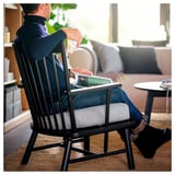 Homme en chaise broche noire utilisant un ordinateur portable. Près du canapé, siège rembourré.