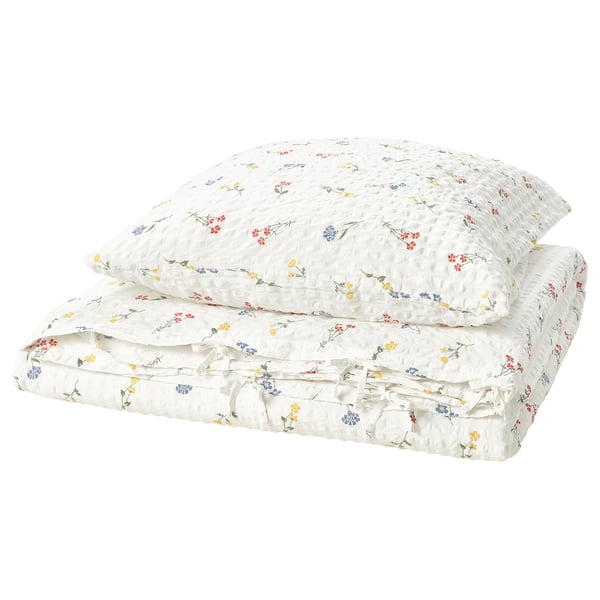 Parure de lit blanche fleurie, texture seersucker légère. Comprend une housse de couette et une taie d’oreiller à motif floral, un doux mélange de coton et de viscose.