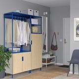 Unité de rangement modulaire PLATSA bleue avec vêtements, étagères et compartiments dans une petite pièce d’entrée.