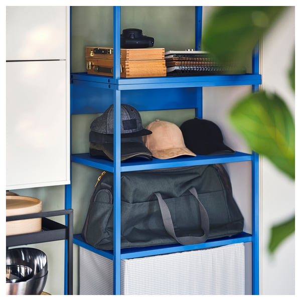 Les étagères de rangement bleues PLATSA peuvent contenir divers objets. Trois étagères avec des sacs gris et noirs, des casquettes et des boîtes en bois. Lumineux, efficace et organisé.