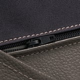 Gros plan de la fermeture éclair de haute qualité sur un luxueux sac en tissu texturé et en cuir.