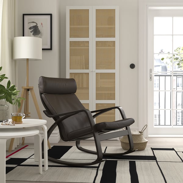 Salon moderne avec fauteuil inclinable en cuir noir, tapis, table d’appoint, lampe, art et balcon.