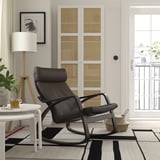 Salon moderne avec fauteuil inclinable en cuir noir, tapis, table d’appoint, lampe, art et balcon.