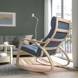 Un élégant fauteuil à bascule en bois de couleur claire avec des coussins bleus se trouve dans un salon confortable, offrant un soutien confortable et un mouvement de balancement doux.