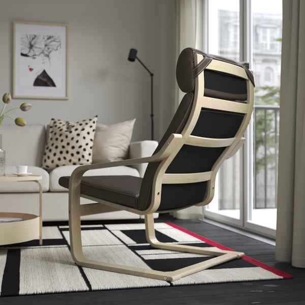 Salon moderne avec un fauteuil inclinable élégant en bois noir et clair près d’une fenêtre, offrant un endroit confortable pour se détendre.