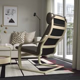Salon moderne avec un fauteuil inclinable élégant en bois noir et clair près d’une fenêtre, offrant un endroit confortable pour se détendre.