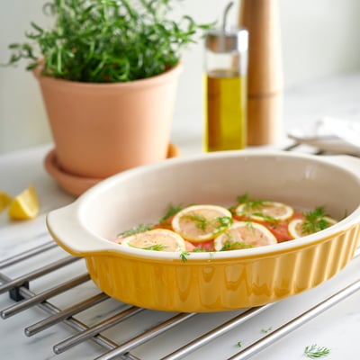 Plat en grès jaune avec des citrons, des herbes, côtelé pour la cuisson et le service.