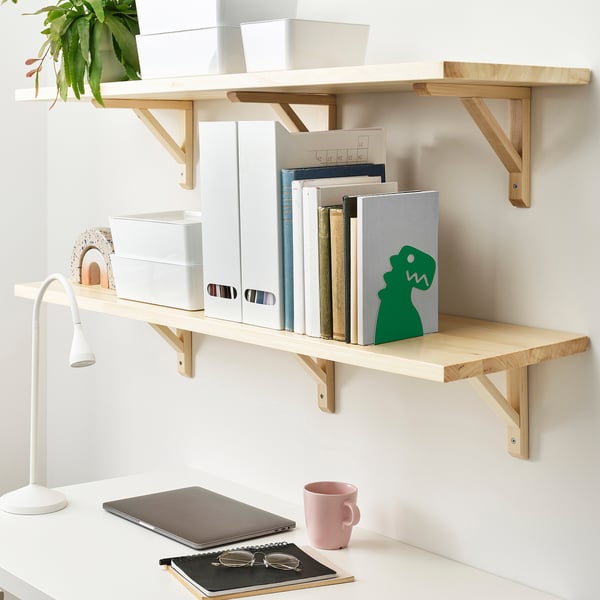 Étagères en bois avec serre-livres de dinosaures, ordinateur portable, tasse et lampe.