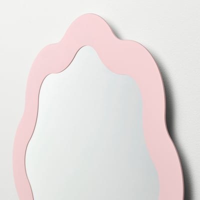 Cette image montre un miroir PRUNKHALLON en rose clair. Il a un cadre ondulé et décoratif et est légèrement convexe. Parfait pour une vanité ou un couloir.