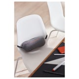 Un petit haut-parleur portable noir est posé sur une chaise blanche.