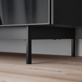 Meuble TV noir moderne avec un design élégant, des pieds en métal robustes et des portes en verre.