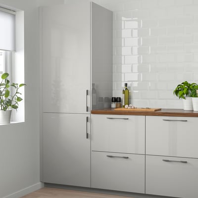 Armoires de cuisine modernes blanches brillantes avec poignées noires élégantes ; Des colonnes flanquent un comptoir présentant les essentiels de la cuisine et des plantes en pot.
