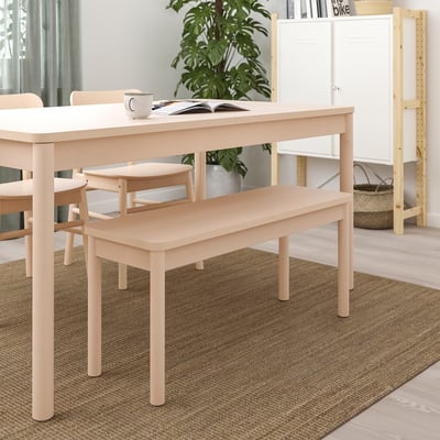 Banc moderne en bois clair sous une table rectangulaire dans une pièce minimaliste.