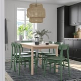 Ensemble de salle à manger moderne avec table beige, chaises vertes et suspension.