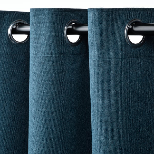 Les rideaux bleu foncé avec œillets pendent en douceur, bloquant la lumière et assurant l’intimité.