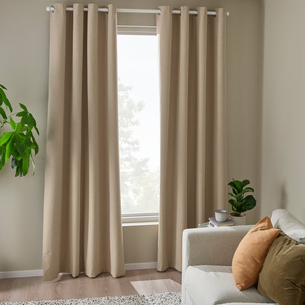 Chambre moderne avec rideaux jaune-beige ROSENMANDEL, conception d’œillets, couvrant une grande fenêtre, complétée par un canapé confortable avec des coussins.