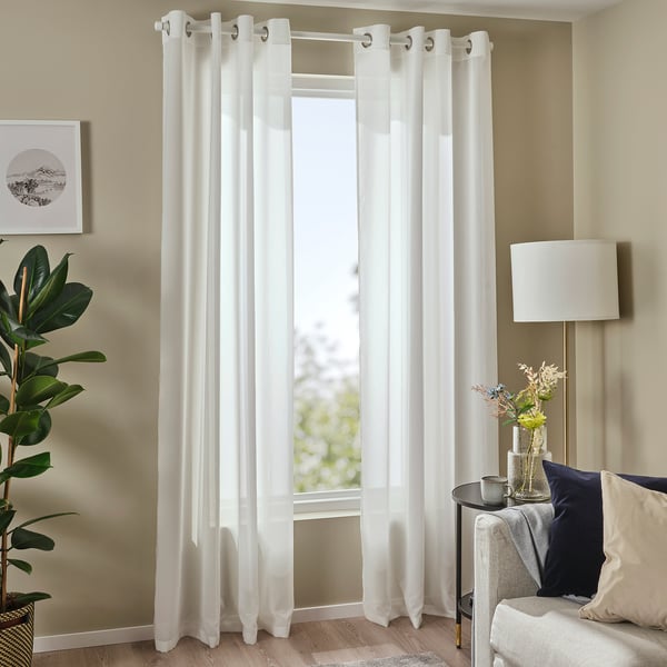 Des rideaux transparents en forme d’œillets sont suspendus près de la fenêtre, à côté de la plante et de la lampe. Nombre de caractères : 48
