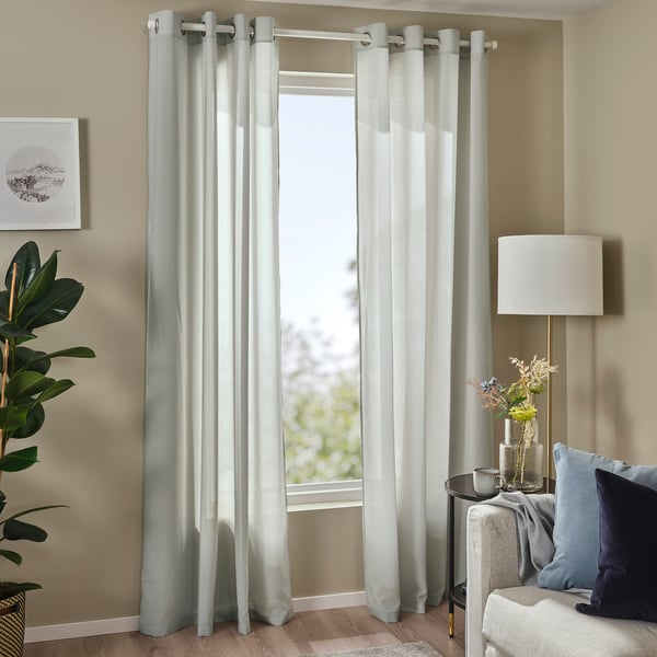 Rideaux roses transparents sur grande fenêtre, décor minimaliste, polyester recyclé, filtre de lumière douce, design moderne, canapé gris, plante.