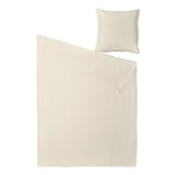 Une parure de lit beige, comprenant une housse de couette et une taie d’oreiller, confectionnée en lin et en coton dans un style chic décontracté et légèrement froissé.