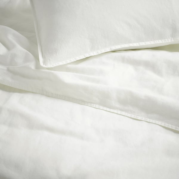 Linge de lit blanc, lisse, net, soigneusement plié, mettant en valeur un tissu de qualité et un design simple.