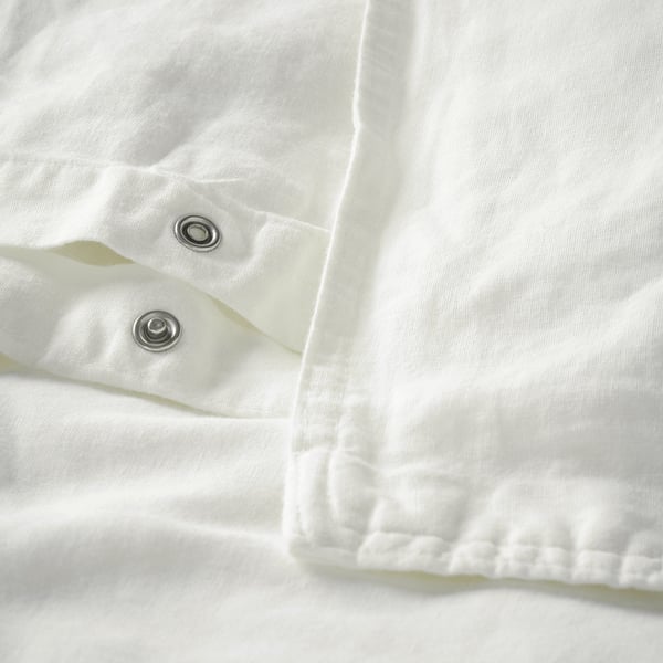 Housse de couette blanche avec boutons-pression et bord froncé.