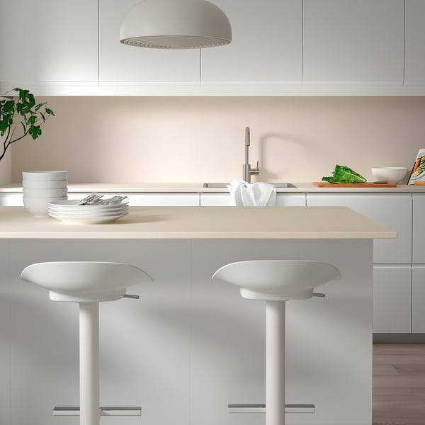 Cuisine blanche moderne avec des murs en porcelaine, deux tabourets, des légumes verts et une suspension.