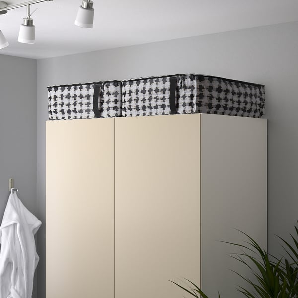 Armoire blanche avec trois cases de rangement à motifs sur le dessus, offrant un rangement sans poussière pour les articles saisonniers.