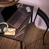 Bureau d’étude noir moderne avec ordinateur portable ouvert, écouteurs, blocs-notes et stylos. Design élégant et fonctionnel, parfait pour le travail ou les études.