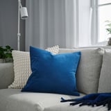 Coussin SANELA bleu sur canapé gris, plus grand que les coussins décoratifs, salon moderne.