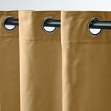 Rideaux en velours beige avec œillets métalliques, glissant en douceur sur tige noire, filtrant la lumière, offrant intimité.