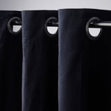 Les rideaux noirs avec linteau à œillets s’accrochent élégamment, montrant un tissu assombrissant la pièce et une fonctionnalité de glissement en douceur.