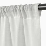 Gros plan de rideaux blancs transparents soigneusement suspendus avec de la texture, montrant une tige et du ruban de tête.